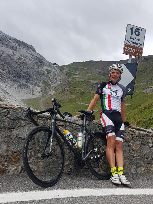 Fietser Arie in haarspeldbocht 16 op 2320 meter op de stelvio pas juli 2022 met uitzicht op de top